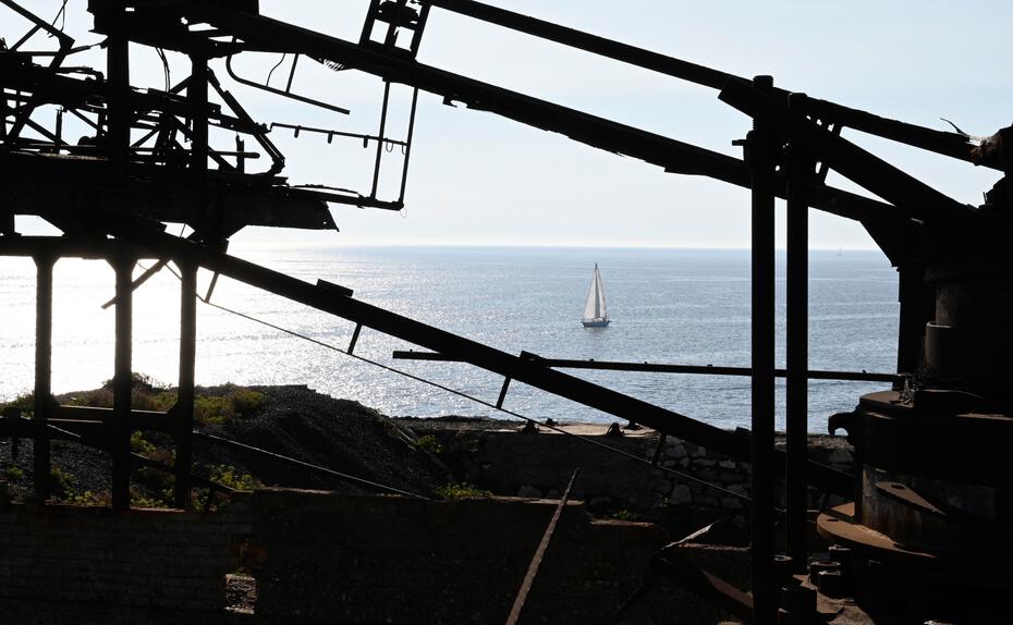 Zahn der Zeit. Zu Kunst in der Landschaft umgearbeitet zeigen sich die verlassenen Bergwerke Elbas. Durch die rostigen Überreste der Miniera del Vallone fällt der Blick auf das strahlend blaue Meer